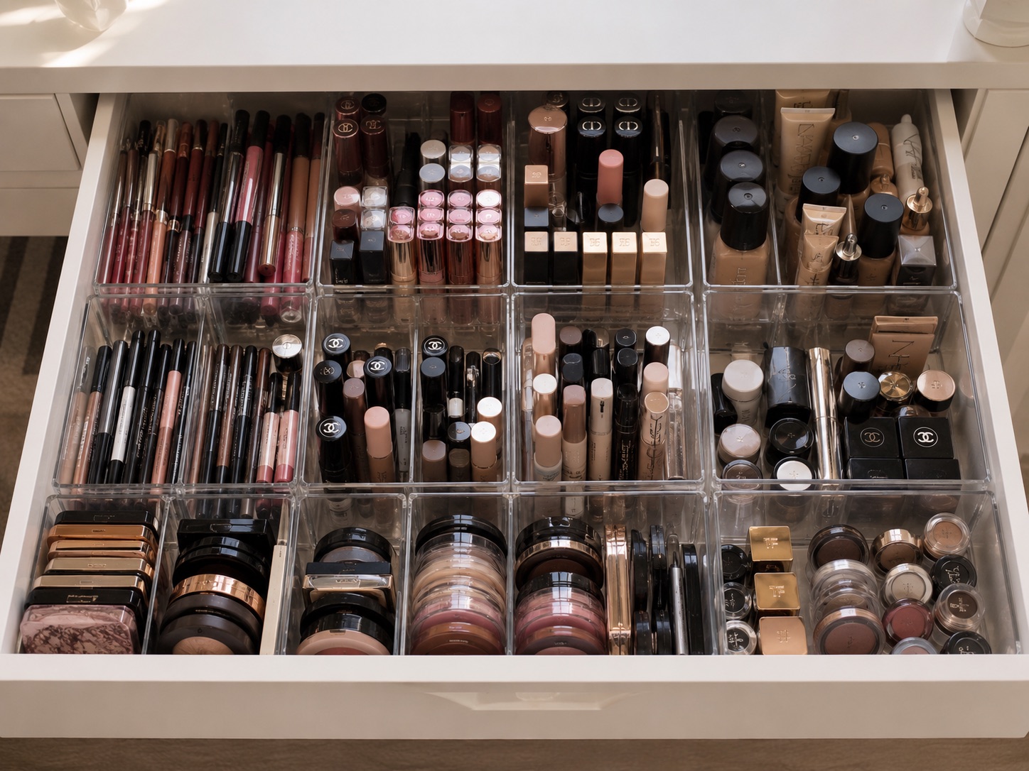 The same drawer after organizing: makeup sorted upright into clear dividers and grouped by type