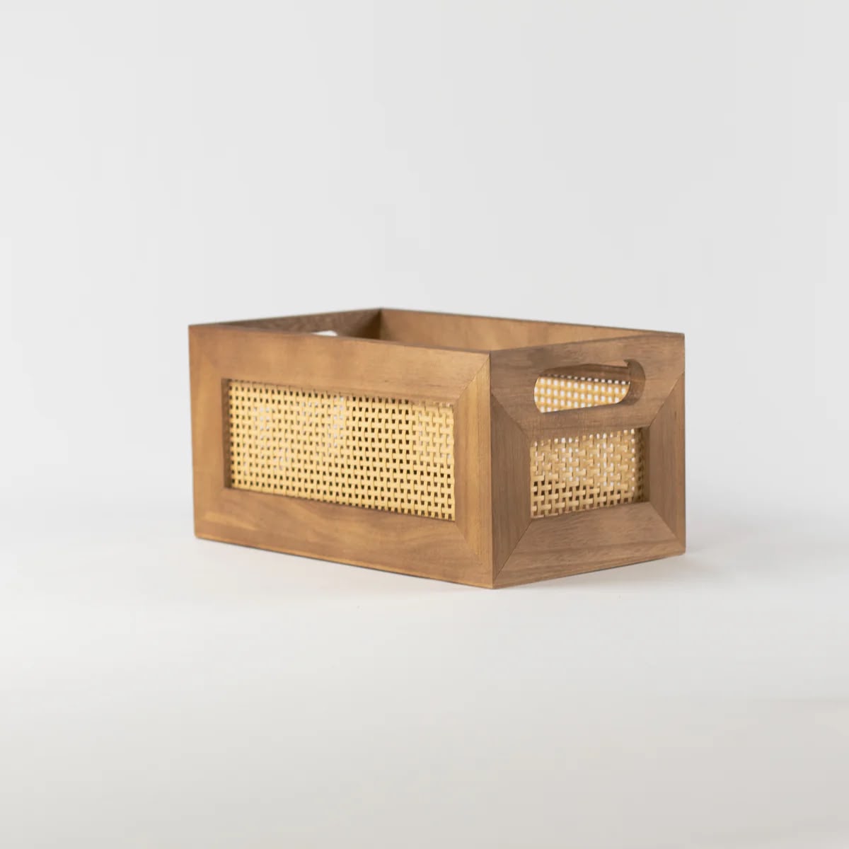 A wooden crate with a woven cane front and cut-out handles